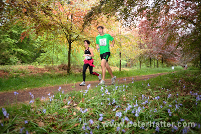two athletes running through a wooded area.