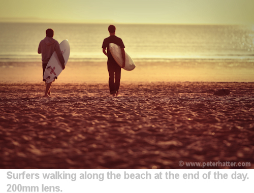 two surfers walking along the beach